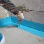 The waterproofing coating is blue. Cover the concrete wall with a cement-polymer waterproofing membrane. Waterproofing with a blue shade brush.
